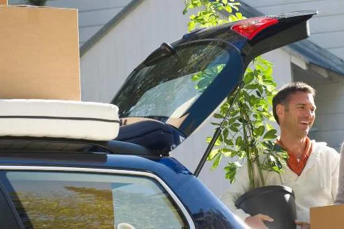 Ein Paar lädt einen Kombi mit Umzugskartons beladen.